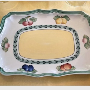 May include: A rectangular ceramic serving platter with a scalloped edge and a green border. The centre features a pale yellow panel surrounded by a green leaf garland. The white rim is decorated with illustrations of cherries, lemons, and plums.