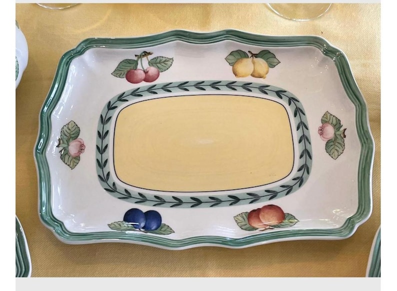 May include: A rectangular ceramic serving platter with a scalloped edge and a green border. The centre features a pale yellow panel surrounded by a green leaf garland. The white rim is decorated with illustrations of cherries, lemons, and plums.