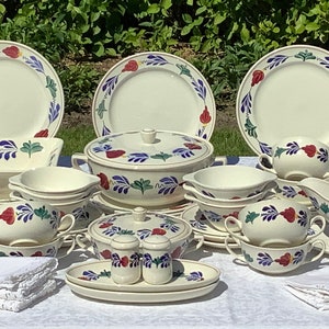 May include: A set of vintage Dutch floral patterned ceramic dinnerware, including plates, bowls, a serving dish, a gravy boat, and a sugar bowl. The set features a white background with blue, green, and red floral designs.