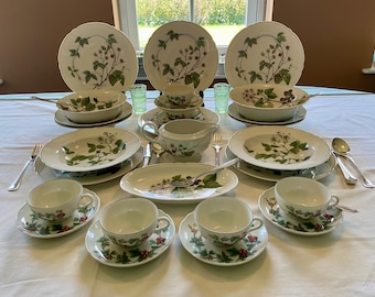 May include: A full vintage dinner service with white porcelain plates, bowls, cups, and saucers. Each item is decorated with a green and red berry and leaf design. Includes serving dishes and a gravy boat.
