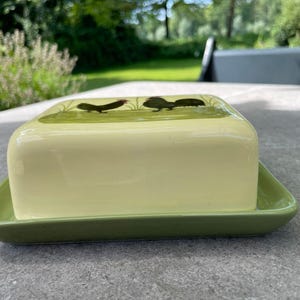 Peut inclure: Un beurrier en c&eacute;ramique vert avec un couvercle repr&eacute;sentant la silhouette de deux coqs sur un fond vert.