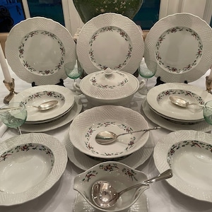 Puede incluir: Un juego de vajilla de cerámica blanca con un patrón floral. El juego incluye un tazón grande para servir, tazones para sopa, platos para cenar y platos para ensalada.