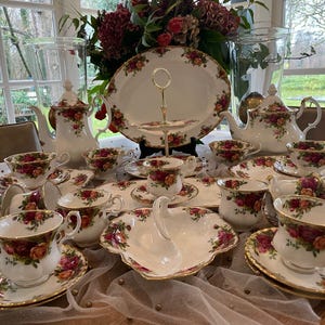 Puede incluir: Un juego de té vintage completo con un estampado floral de rosas. El juego incluye tazas de té, platillos, teteras, fuentes para servir y una bandeja de servicio de varios niveles. La porcelana tiene ribete dorado.