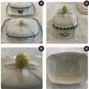 May include: A white ceramic butter dish with a lid featuring a yellow fruit-shaped handle, green leaf accents, and a green border. The dish is decorated with various fruit illustrations including plums, lemons, and a pink flower on the sides.