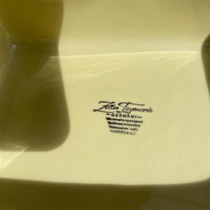 Peut inclure: Un plat carr&eacute; en c&eacute;ramique jaune avec le texte "Zeller Fayence - GERMANY - Mikrowellengeeignet - Sp&uuml;lmaschinenfest - Geschirrsp&uuml;ler - safe - VANDOREVALT" imprim&eacute; au fond.