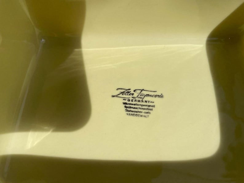 Peut inclure: Un plat carr&eacute; en c&eacute;ramique jaune avec le texte "Zeller Fayence - GERMANY - Mikrowellengeeignet - Sp&uuml;lmaschinenfest - Geschirrsp&uuml;ler - safe - VANDOREVALT" imprim&eacute; au fond.