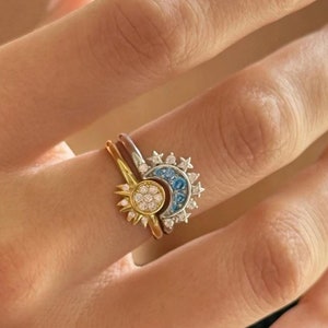 Könnte beinhalten: Ein goldener Ring mit einem Sonnenmotiv und ein silberner Ring mit einem Halbmondmotiv. Beide Ringe sind mit kleinen Diamanten besetzt.