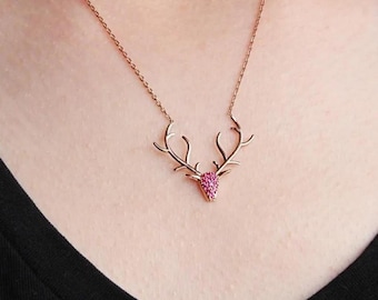 Könnte beinhalten: Eine Halskette aus Roségold mit einem pinkfarbenen Kristall-Hirschkopf-Anhänger.