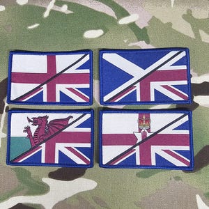 Può includere: Quattro toppe rettangolari con bordo blu, ciascuna con una variazione del design Union Jack. Le toppe incorporano simboli regionali, tra cui un drago, una corona e una croce, su uno sfondo mimetico.