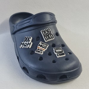 May include: Blue slip-on shoe with various colourful charms attached. The charms have text that reads "Dog Mom", "Dog Dad", "I Prefer Dogs Over People", and "Coffee Because Adulting Is Hard".