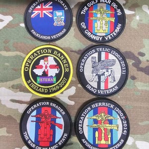 Può includere: Sei toppe militari circolari con vari disegni e testo. Le toppe presentano bandiere, emblemi e testo come "Operation Corporate Falklands Veteran", "The Gulf War (90-91) Op Granby Veteran" e "Operation Banner N Ireland 1969-2007".