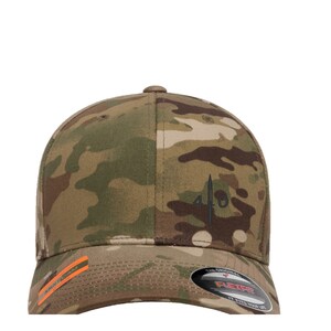 Peut inclure: Une casquette de baseball camouflage avec un logo brodé noir qui dit "410" avec un design d'épée. La casquette est fabriquée par Flexfit et a une étiquette noire et orange sur le côté.