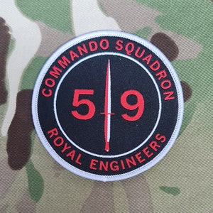 May include: A white, round patch with black and red text. The text reads "Commando Squadron 519 Royal Engineers". A white sword is in the centre of the patch.
