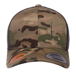 May include: A camouflage-patterned baseball cap with a black mesh back and a small black dagger embroidered on the front. The cap has a black snap closure and a brown leather strap with the text "The Authentic Snapback" printed on it.