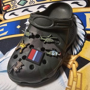 Op de afbeelding: Een witte keramische mok met een zwart handvat en de tekst "But First, Coffee" in een zwarte, vette letter. De mok staat op een wit oppervlak.