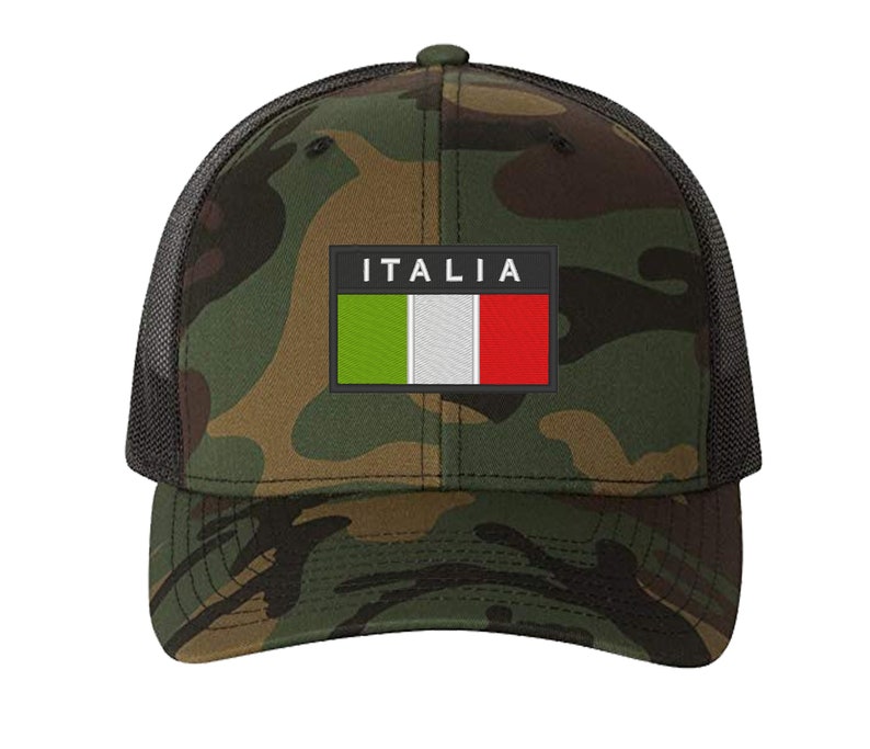 May include: A camouflage trucker hat with a black mesh back. The hat features a patch with the Italian flag and the word "ITALIA" in white letters.