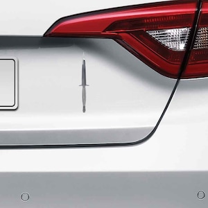 May include: A silver car with a black knife sticker on the back.