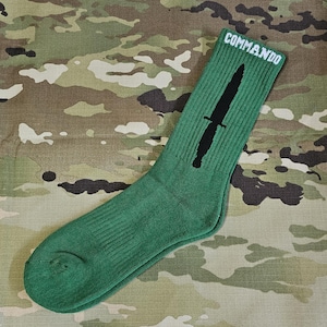 May include: Green crew socks with a black silhouette of a knife and the word "COMMANDO" in white lettering on the top of the sock.