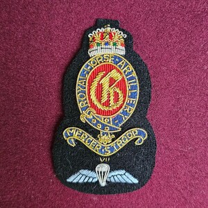 May include: A black embroidered patch with a gold crown, a red and blue shield with a gold letter "K" inside, and the text "Royal Horse Artillery" and "Mercer's Troop VII".