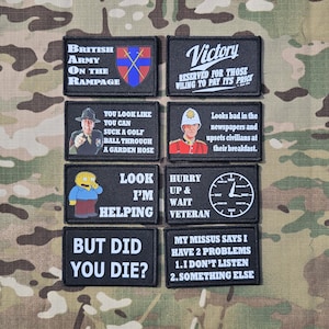 May include: A collection of eight rectangular black morale patches with white text and graphic illustrations. The patches feature various humorous phrases, military-themed imagery, and cartoon characters, all arranged in a grid on a camouflage background.