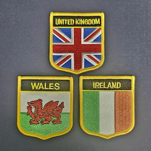 May include: Three embroidered patches in the shape of shields with gold trim. The top patch features the Union Jack flag with the text "UNITED KINGDOM". The left patch features a red dragon on a green and white background with the text "WALES". The right patch features the Irish flag with the text "IRELAND".