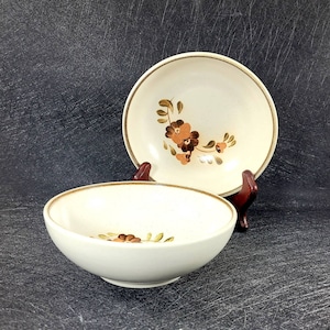 May include: Two brown and white ceramic bowls with a floral design. The bowls are stacked on top of each other.