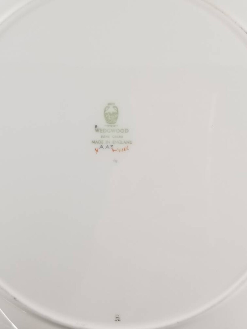 May include: White ceramic plate with a green Wedgwood logo and the text "Bone China Made in England" and a red stamp that says "YAA2".