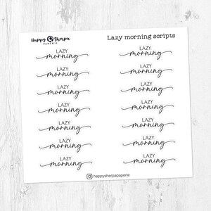 以下が含まれることがあります： 「Lazy morning」の文字が筆記体で書かれた白いステッカーシート。ステッカーは行と列に配置されています。シートには「Lazy morning scripts」の文字とHappy Sherpa Paperieのロゴも含まれています。