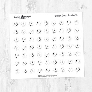 Könnte beinhalten: Ein Bogen Aufkleber mit dem Text "Tiny dot clusters" und dem Happy Sherpa Papeterie Logo. Die Aufkleber sind kleine, schwarze Punktcluster auf weißem Hintergrund. Der Bogen liegt auf einer hellen Holzoberfläche.