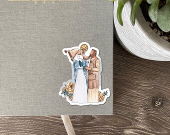 May include: A sticker featuring an illustration of two figures in religious attire, one holding a baby. The sticker is placed on a gray journal with the gold text "EVERY SACRED SUNDAY". Decorative yellow flowers are at the bottom of the sticker.