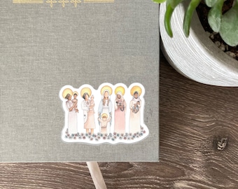 May include: A sticker featuring an illustration of several women holding babies, each with a halo. The sticker is placed on a gray journal with the gold text "EVERY SACRED SUNDAY". The sticker has a floral border.