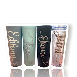 Può includere: Quattro bicchieri personalizzati con i nomi "Emily", "Trinity", "Eleanor" e "Sunny" in strass. I bicchieri sono di vari colori, tra cui blu, verde e nero.