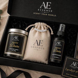 May include: A black gift box containing a 198 g Velvet Desire candle, a beige drawstring pouch with an Essence bead bracelet, and a 118 ml Velvet Desire home fragrance mist. The box lid features the AE Essence logo and the text Scent Your World.
