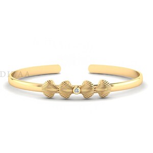 Peut inclure: Un bracelet jonc en or avec trois breloques en forme de coquillage et un seul diamant au centre.