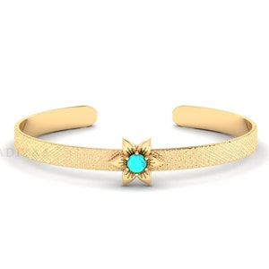 Könnte beinhalten: Ein goldenes Armreif-Armband mit strukturierter Oberfläche und einem türkisfarbenen Blumenanhänger.