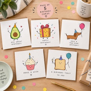May include: A pack of five square birthday cards featuring hand-drawn illustrations of an avocado with the text AVO GREAT BIRTHDAY, a gift box with HAPPY BIRTHDAY, a dachshund with HAVE A PAW-SOME BIRTHDAY, a cupcake with MAKE A WISH, and toast with A BIRTHDAY TOAST TO YOU.