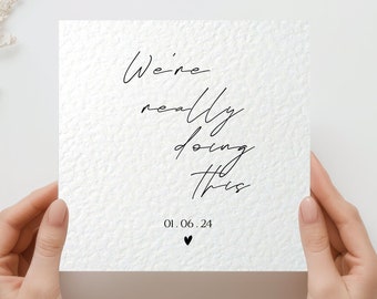 May include: A white card with black calligraphy that reads "We're really doing this" and the date "01.06.24" with a small heart symbol.