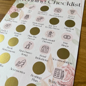 May include: A wedding checklist with gold circles and pink floral accents. Each circle has a different task to complete, such as book a band, order the cake, and send invitations.