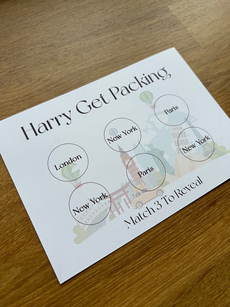 May include: A white card with the text "Harry Get Packing" printed in black. The card has six circles with the names of cities printed inside: London, New York, Paris, New York, Paris, and New York. The text "Match 3 To Reveal" is printed at the bottom of the card.