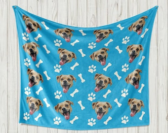 May include: A blue fleece blanket with a repeating pattern of dog faces, paw prints, and bone shapes. The dog faces are all the same, but the blanket is personalized with different dog faces.