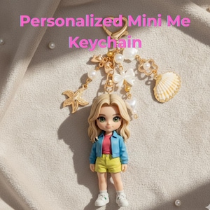 May include: A personalized Mini Me keychain featuring a miniature doll with blonde hair, green eyes, and a blue jacket. The keychain includes gold-colored charms like a starfish, seashell, and pearls. The text "Personalized Mini Me Keychain" is displayed in pink.