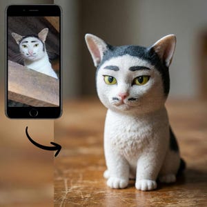 Puede incluir: Figura de gato de cerámica con un diseño único. El gato es blanco con marcas negras y presenta cejas estilizadas y un pequeño bigote. El gato está sentado sobre una superficie de madera, y una foto de un gato similar se muestra en un teléfono inteligente.