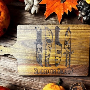 May include: Wooden cutting board with a handle, featuring engraved knife designs. The board has the text "Sliced or Diced?" and is surrounded by fall foliage and pumpkins. A decorative item for Halloween.