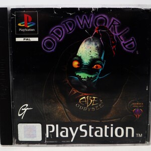 May include: A PlayStation game case for Oddworld: Abe's Oddysee. The cover features a dark background with a green and blue creature with large eyes and the game title in purple. The PlayStation logo is visible.