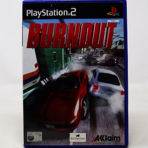 Puede incluir: Caja de juego de PlayStation 2 para Burnout, un juego de carreras. La portada presenta un coche deportivo rojo conduciendo por una calle de la ciudad, con un camión de plataforma en el fondo.