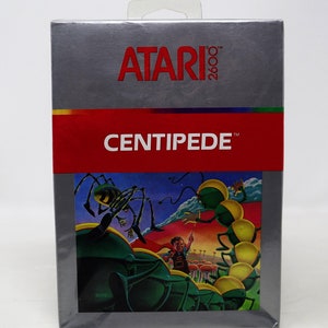 May include: A silver Atari 2600 game cartridge box with a red label that says "CENTIPEDE". The box features a colorful illustration of a centipede, a spider, and a person playing a game.
