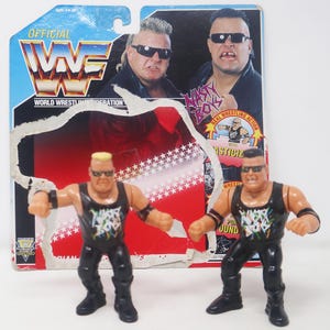 May include: Two black and white action figures of wrestlers from the WWF, the Nasty Boys. The figures are wearing black tank tops with the words "Nasty Boys" printed on them. The figures are posed in a fighting stance.