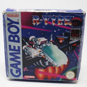 May include: A blue Game Boy game cartridge box featuring a white and blue spaceship on the front. The box displays the text "R-Type" in large, white letters. The text "Game Boy" is in large, white letters on the left side of the box. The text "Nintendo" is in small, white letters on the top left corner of the box.