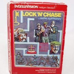 Op de afbeelding: Een vintage rode Intellivision videogamebox voor "Lock 'N Chase" van Mattel Electronics. De doosafbeelding toont cartoonillustraties van personages in een doolhof, met de titel van het spel in geel. De doos is licht beschadigd.