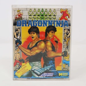 Può includere: Una cartuccia di videogioco vintage per il computer Spectrum 48/128. Il gioco si chiama "Dragon Ninja" ed è prodotto da Data East. La cartuccia è in una custodia di plastica trasparente con un'etichetta colorata che presenta due uomini muscolosi in pose di combattimento.
